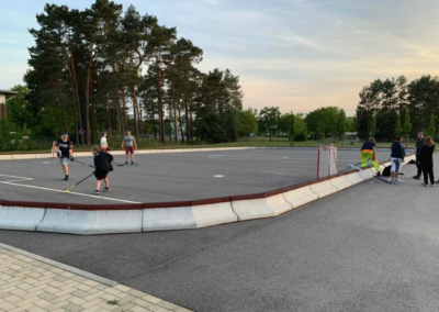 Kinder und Jugendliche spielen Unihockey auf einem abgesteckten Beton-Platz