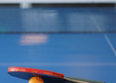 Tischtennisschläger und Ball liegen auf einer blauen Tischtennisplatte