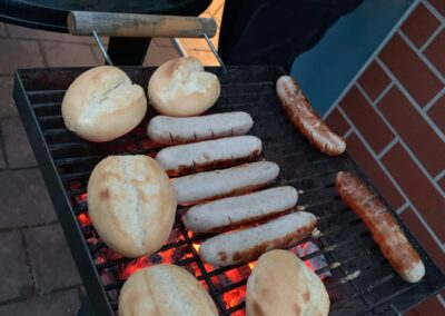 Bratwürste und Brötchen liegen auf einem Grill
