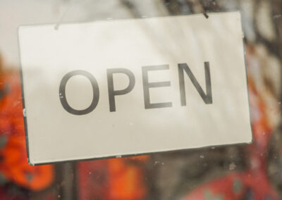 Schild mit der Aufschrift "OPEN" hängt hinter einer Fensterscheibe